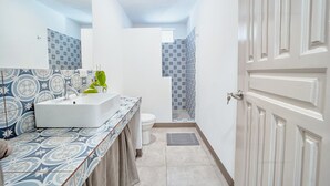 Een badkamer met een wit wastafelmeubel, een spiegel en betegelde vloeren.