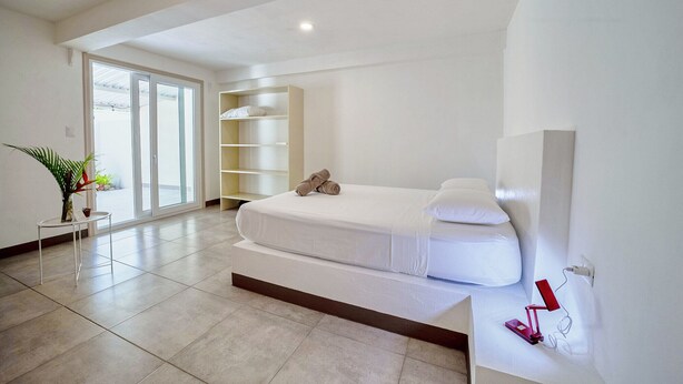 Een moderne slaapkamer met een bed, een inbouwkast en een glazen schuifdeur naar een balkon.