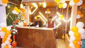 Un mostrador de recepción con detalles de madera, flanqueado por arreglos de globos y decoraciones florales.