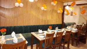 Un restaurante con paredes de madera a rayas, mesas dispuestas con servilletas blancas y globos anaranjados y blancos.