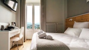 Habitación de hotel con cama, escritorio, silla, televisión y vistas al exterior.