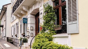 Un edificio con balcón, un cartel y un seto cuidado.