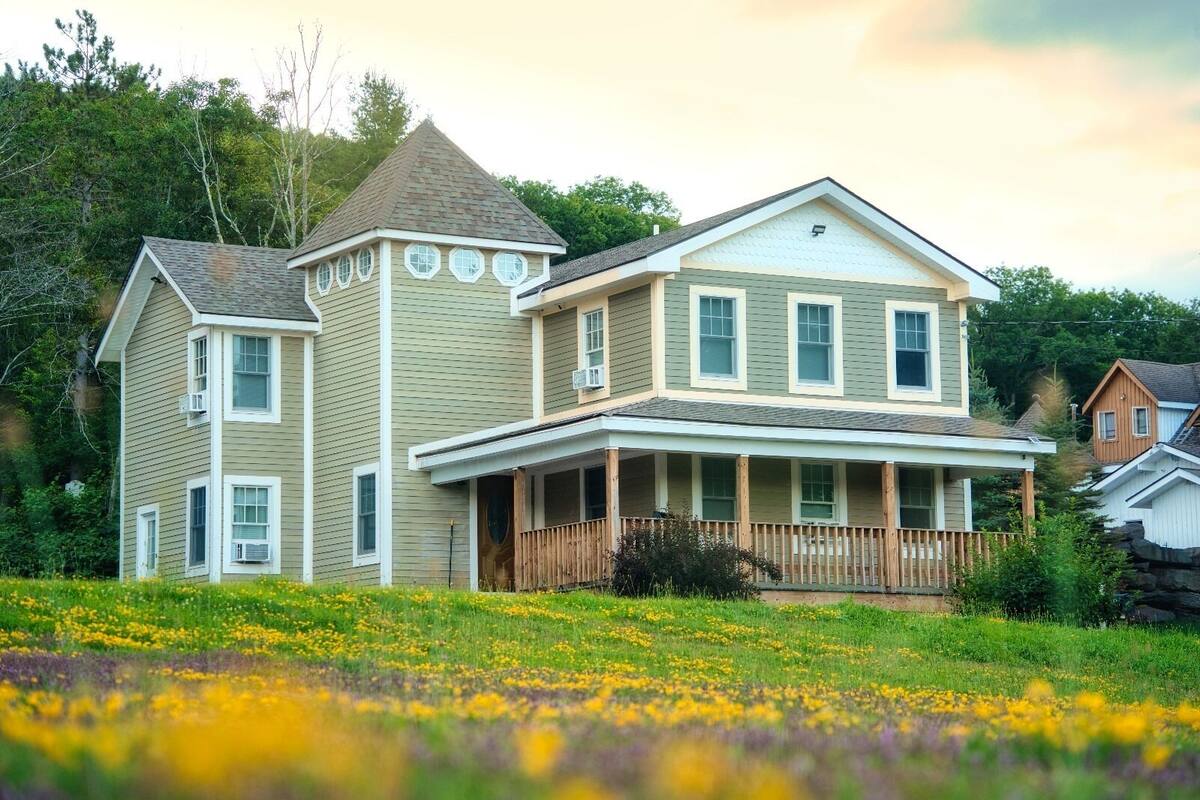 A two-story house with a porch and a small tower-like structure.