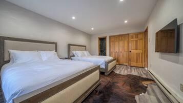 A bedroom with two beds, a wooden wardrobe, and a mounted TV.