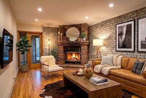 Una sala de estar acogedora con chimenea, un sofá, una mesa de centro y un sillón.