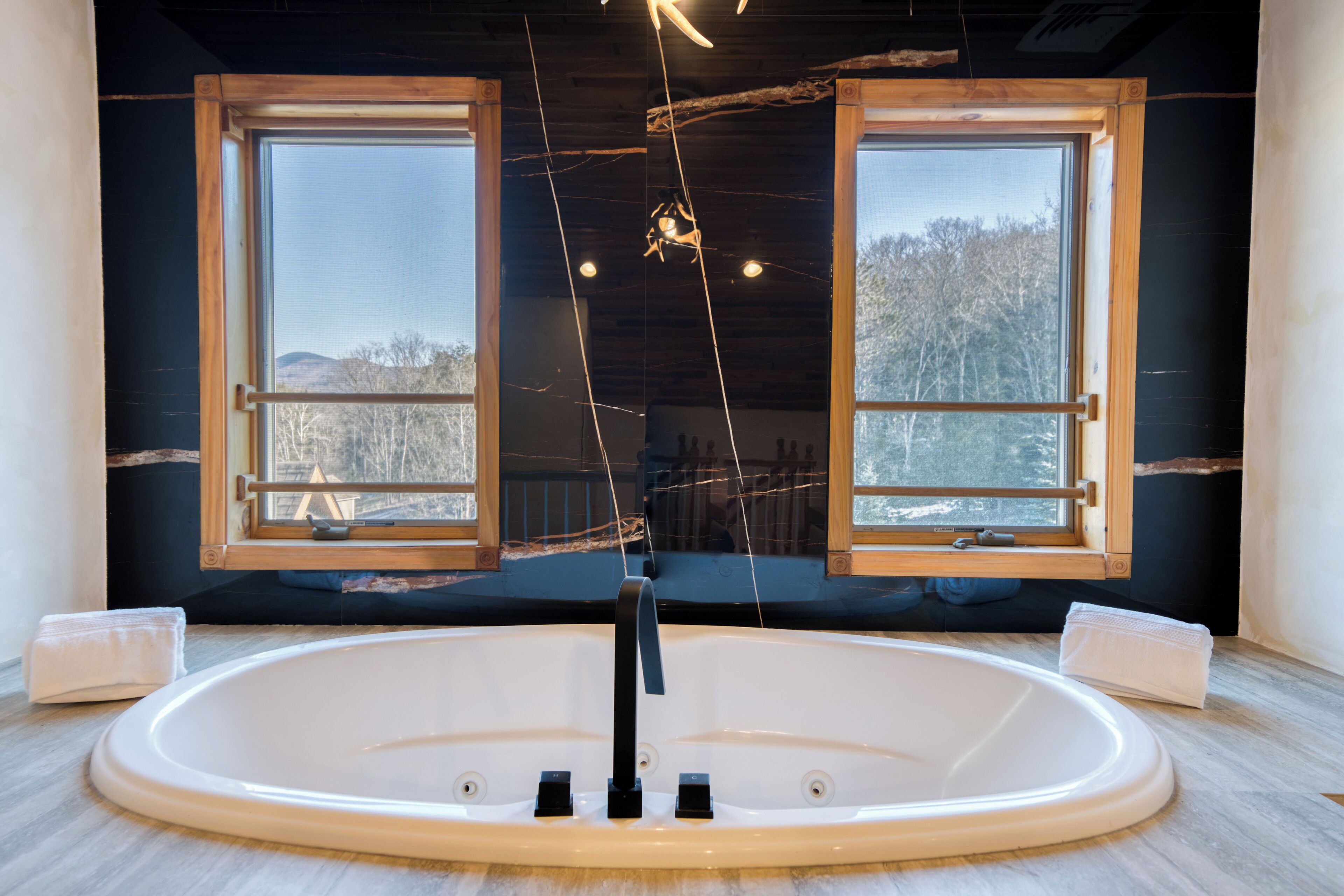 Een groot, ovaal bad in een kamer met twee ramen.