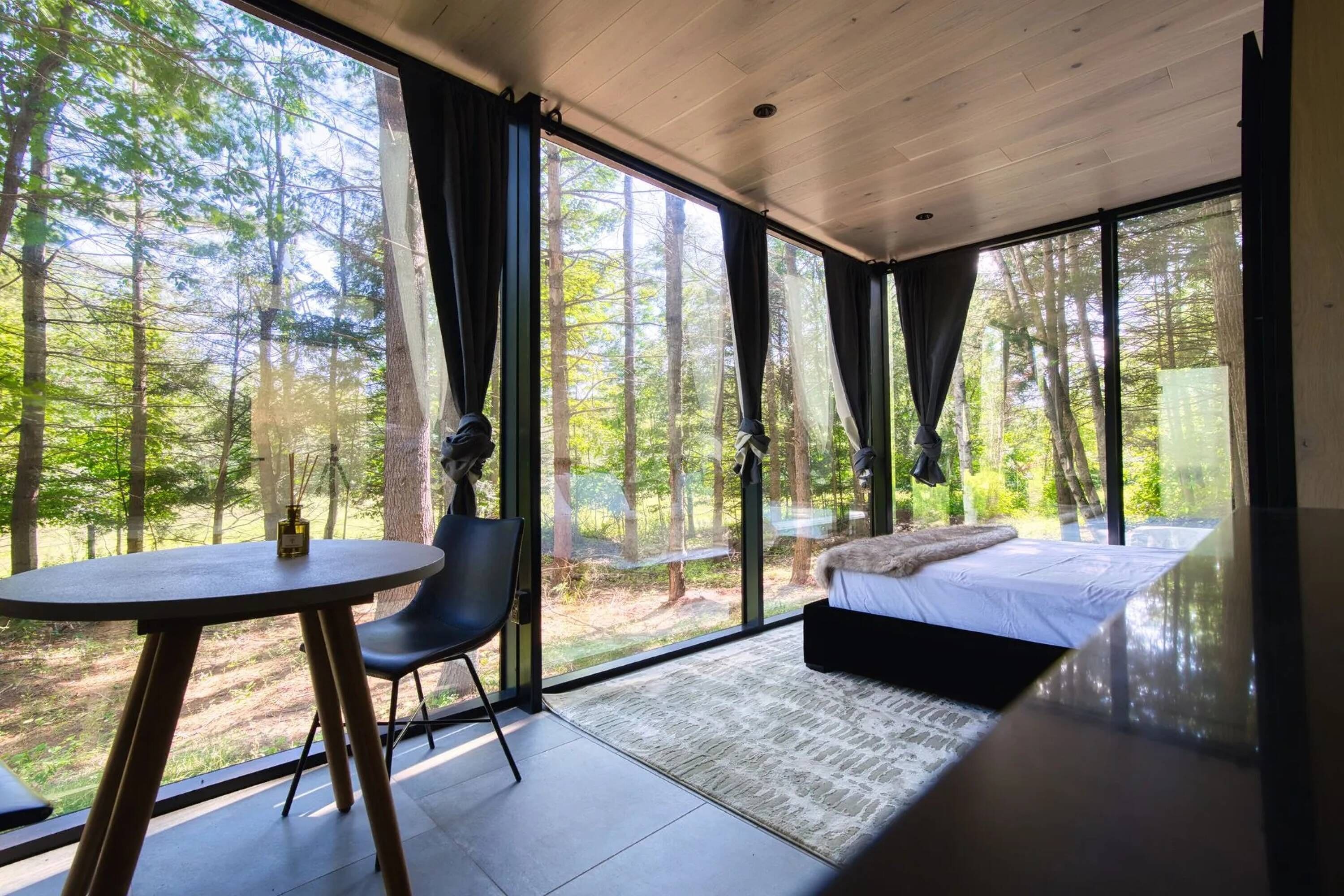 Un dormitorio moderno con un ventanal grande, una cama, una silla y una mesa.