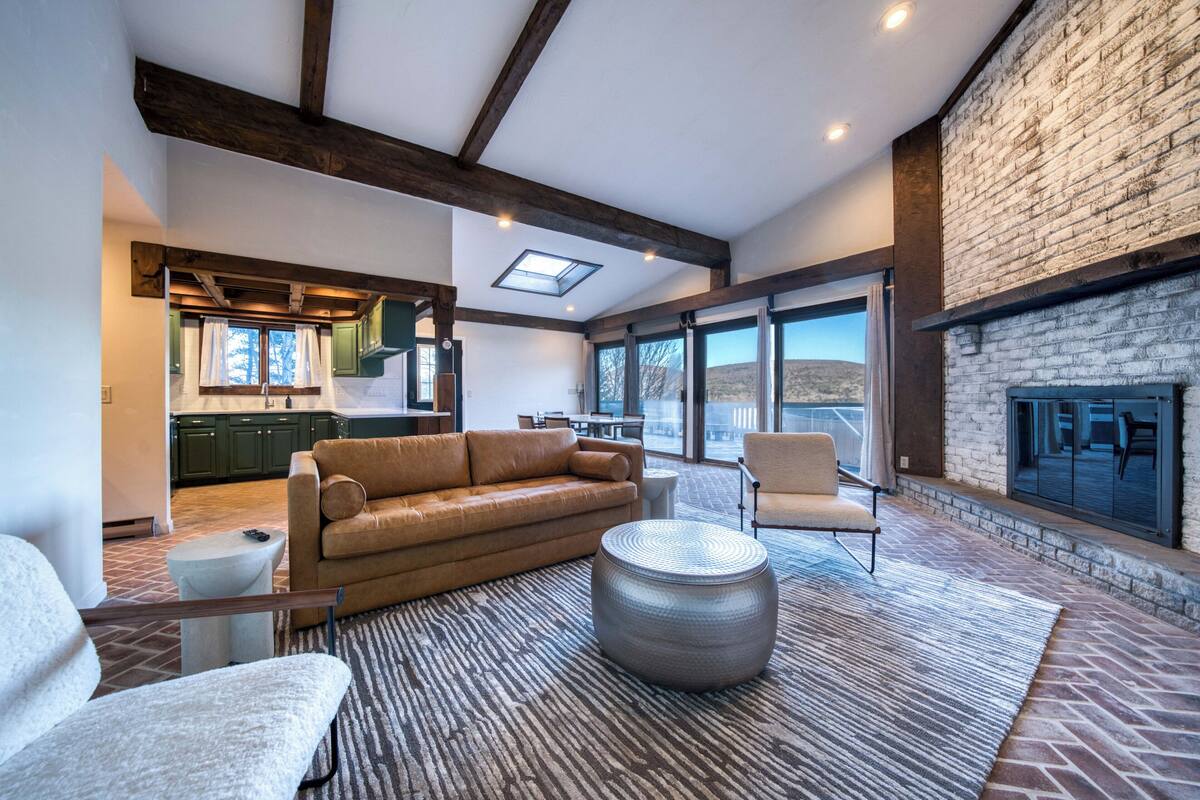 A spacious living area with a large sofa, a round ottoman, and a fireplace.