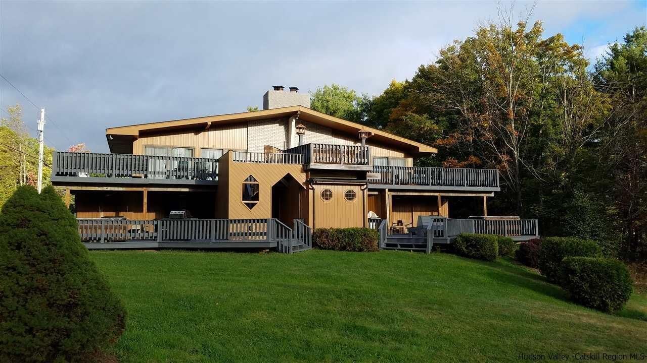 A two-story house with a balcony on the upper level, a garage, and a well-maintained lawn.