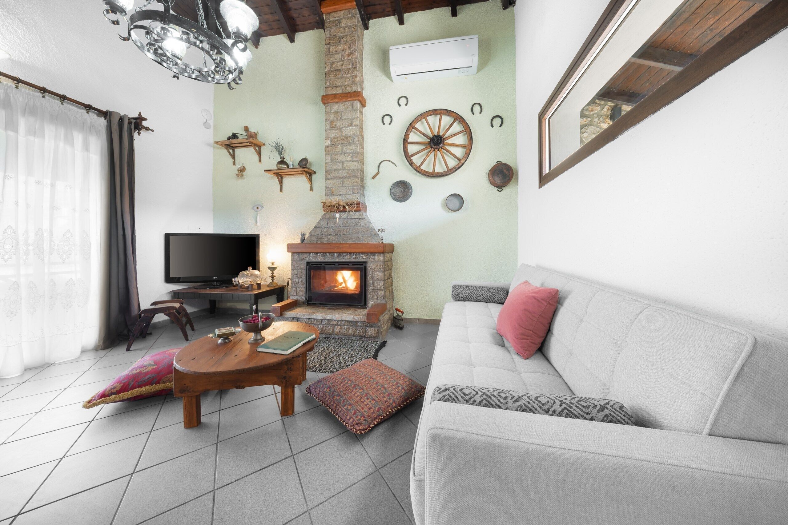 A cozy living room with a stone fireplace, a sofa, a television, and a coffee table.
