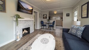 A living room with a fireplace, a sofa, and a dining area with chairs. - Great Location! 2 Houses for large groups!! (Grand Junction)
