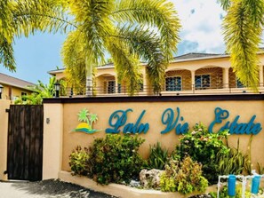 Un bâtiment portant une enseigne indiquant « Lahaina Vie Estate » et une zone aménagée avec des plantes tropicales.