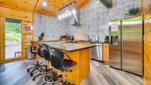 A modern kitchen with wooden cabinetry, a marble backsplash, and stainless steel appliances. - Cedar Lodge - Location can’t be beat.   Many repeat customers! (Pigeon Forge)
