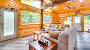 A log cabin with a wooden interior, a sofa, a coffee table, and a flag on the wall. - Cedar Lodge - Location can’t be beat.   Many repeat customers! (Pigeon Forge)