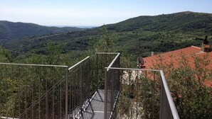 Eine Metalltreppe führt zu einer Terrasse mit Blick auf eine hügelige Landschaft.