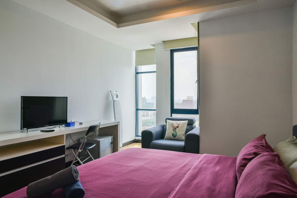 Habitación de hotel con cama, televisor, escritorio y silla.