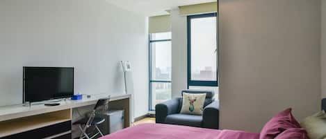 Habitación de hotel con cama, televisor, escritorio y silla.