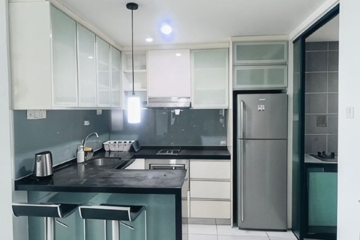 Una cocina moderna con una isla central, electrodomésticos de acero inoxidable y un ventanal amplio.