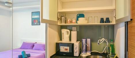 A compact room with a bed, kitchenette, and a small bathroom.