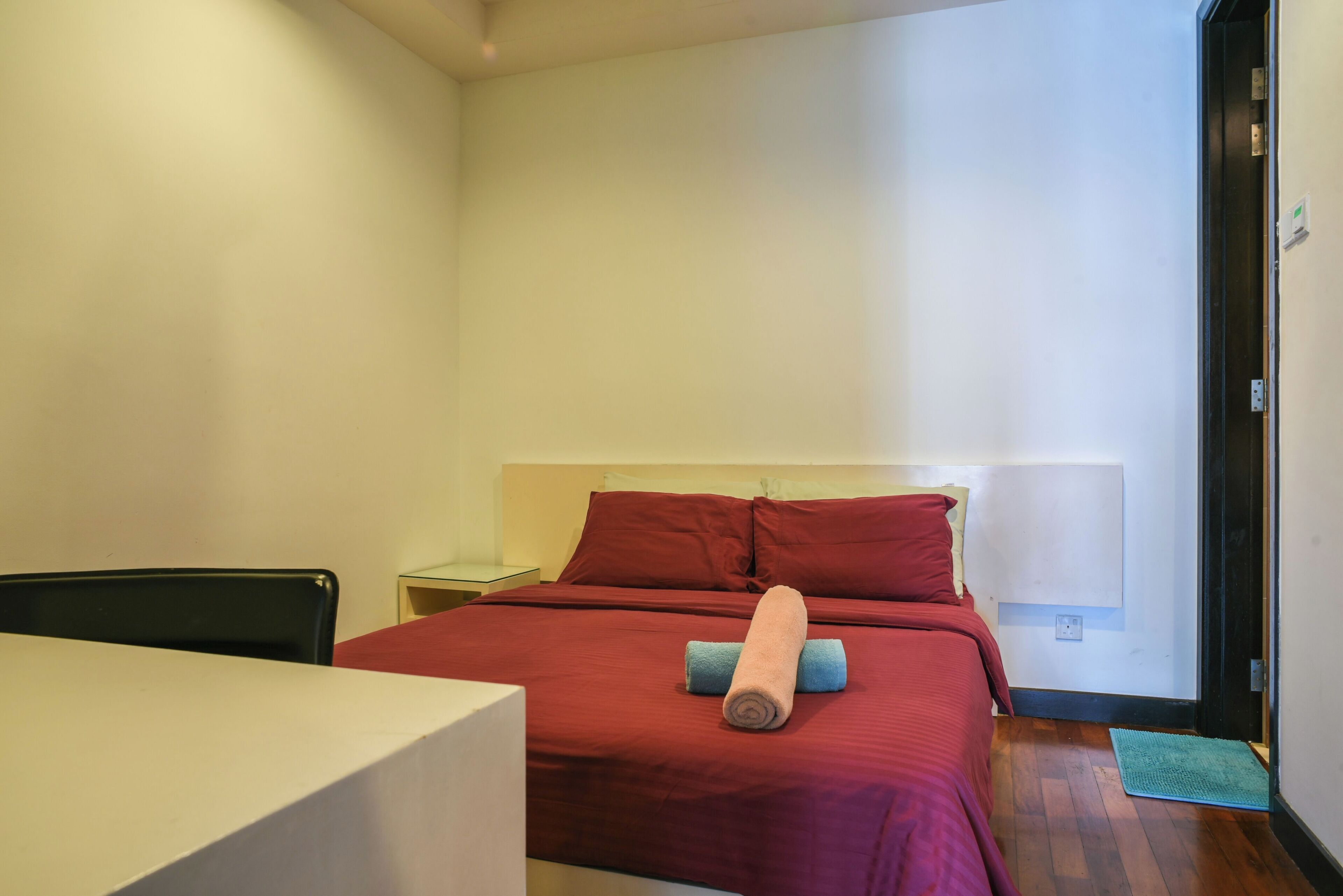 A small, neatly arranged bedroom with a bed, a nightstand, a chair, and a table.