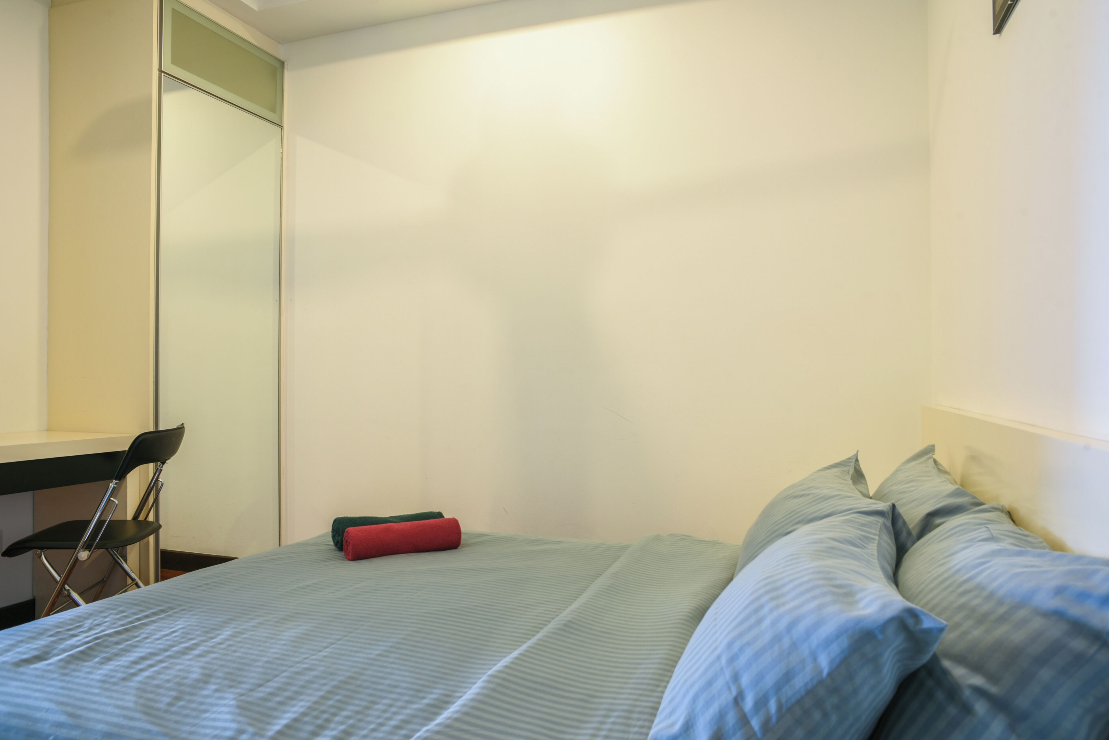 Une chambre à coucher avec un lit, des oreillers, une chaise et un bureau.