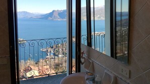 Un baño con un ventanal grande que ofrece vistas a un lago y montañas.