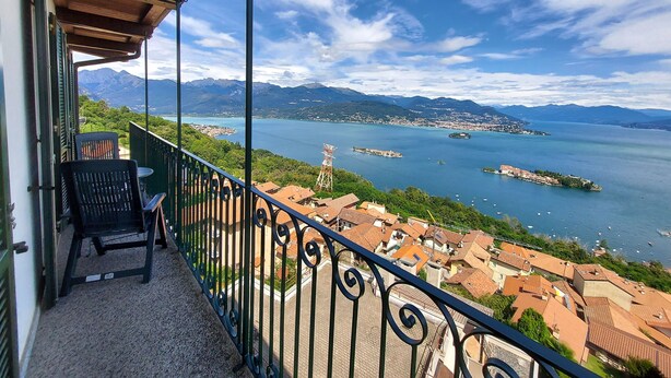 Un balcón con vistas a un lago, montañas y un pueblo.
