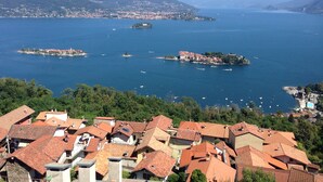 Un pueblo costero con edificios de tejas color terracota, un puerto deportivo con barcos y montañas al fondo.