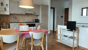 Una cocina compacta equipada con microondas, tostadora y un comedor con sillas y mesa.
