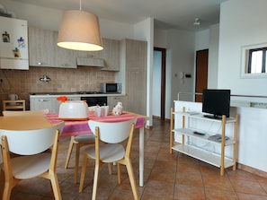 A compact kitchen with a microwave, toaster, and a dining area with chairs and a table. - A window 4 overlooking Lake Maggiore! (Stresa)