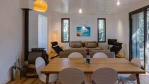 Un'area pranzo moderna con un tavolo di legno, sedie bianche e un quadro appeso al muro.