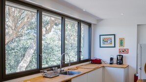 Una cucina moderna con ampie finestre, lavastoviglie e macchina da caffè.