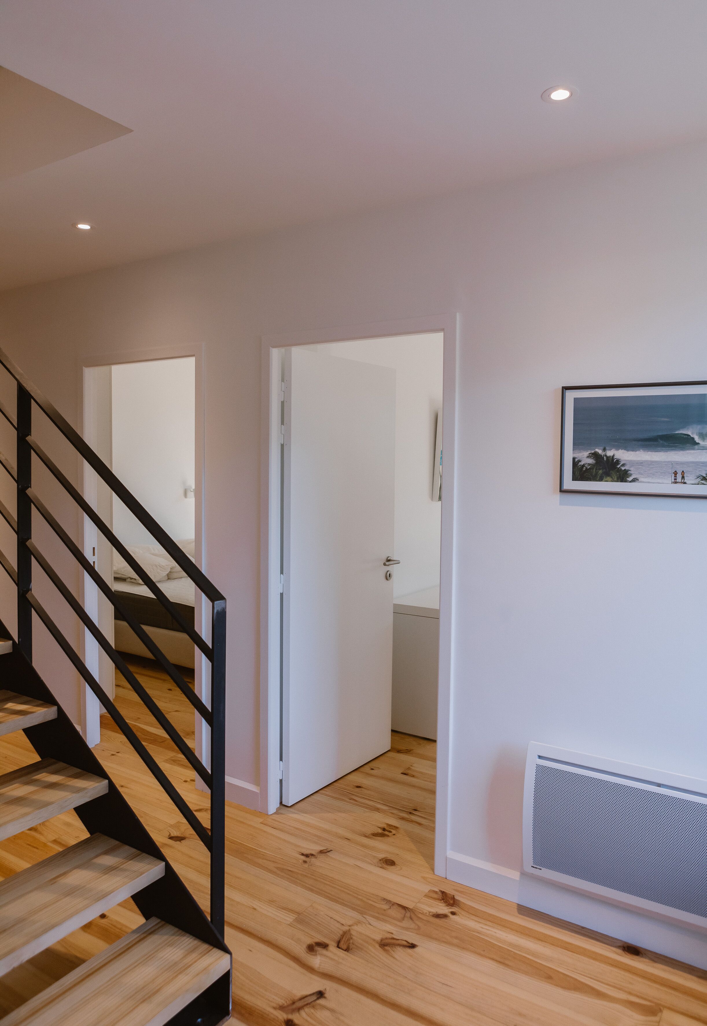A staircase with wooden steps and black railings leading to a bedroom with a white door.