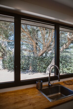 Une cuisine dotée d’une grande fenêtre, d’un évier et d’un plan de travail en bois.