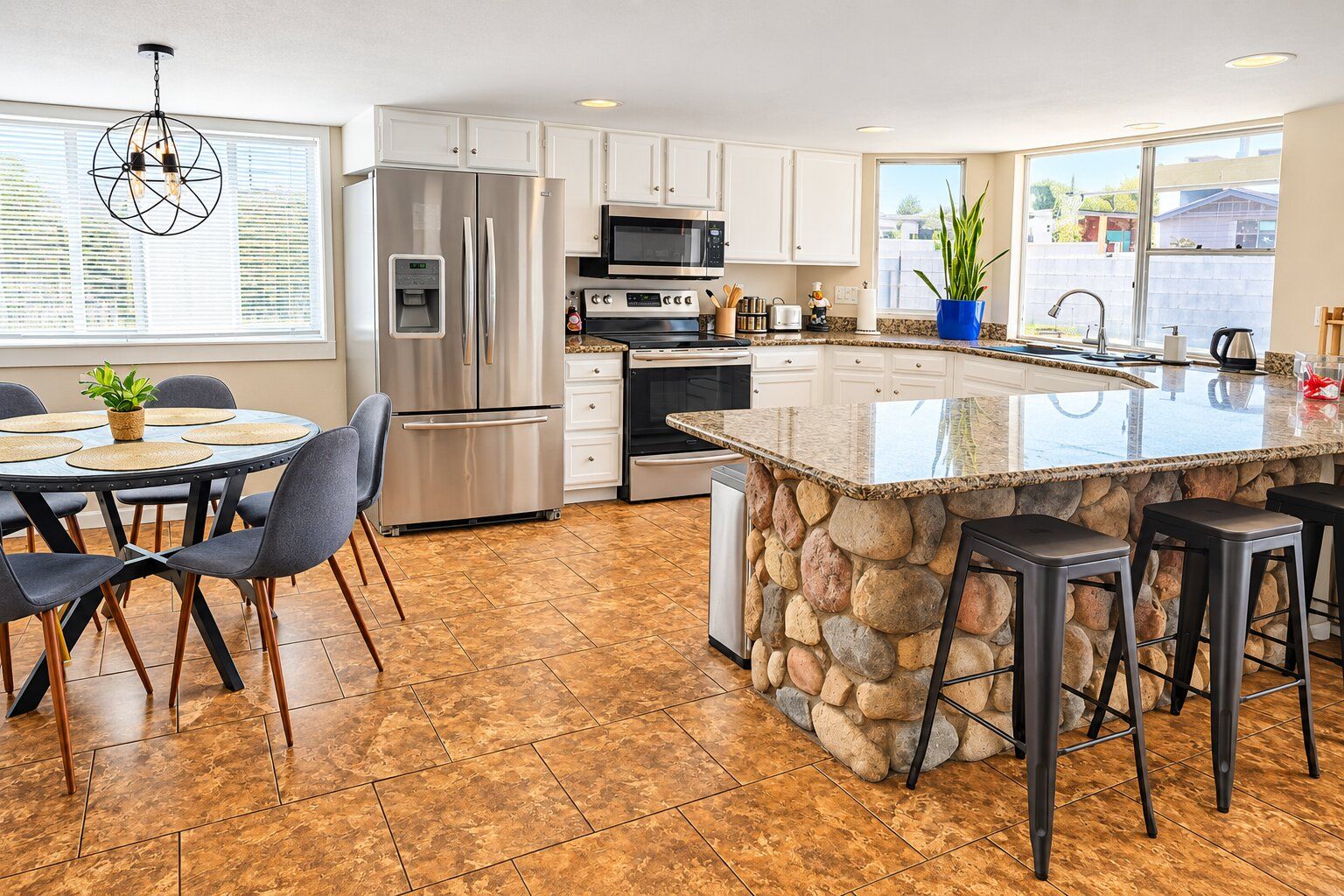 Cozinha moderna com ilha central, eletrodomésticos de aço inoxidável e parede decorada com pedra.