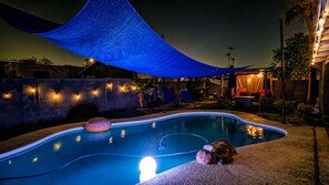 A swimming pool with a blue shade sail overhead, a lounge area with chairs, and a small water feature. - kingbed+divingpool+firepit,
near tsmc, mayo clinic, deer valley airport (Phoenix)