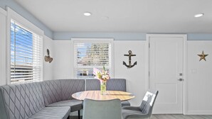 A dining area with a round table, grey upholstered seating, and decorative elements like an anchor and star on the walls. - Modern craftsman home close to all Garibaldi has to offer. Dog Friendly! (Rockaway Beach)