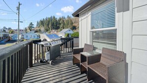 A wooden deck with a grill, wicker furniture, and a view of houses and trees. - Modern craftsman home close to all Garibaldi has to offer. Dog Friendly! (Rockaway Beach)