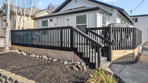 A single-story house with a black metal fence, a wooden deck, and a small staircase leading to the front door. - Modern craftsman home close to all Garibaldi has to offer. Dog Friendly! (Rockaway Beach)
