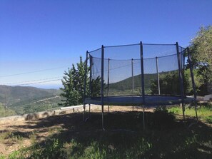 A trampoline with a safety net, surrounded by natural landscape and hills. - Six - Accommodations beneath the pool with panoramic views, nestled among olive trees, 15 km from the sea (Villa Viani)