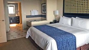 A hotel room with a large bed, a nightstand, a bedside table, a mirror, and a view of the bathroom. -  -- RECENTLY REDUCED!! Marriott Grand Chateau---Great Formula 1 viewing Nov 2023 (Las Vegas)