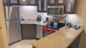 A modern kitchen with stainless steel appliances, granite countertops, and dark wooden cabinets. -  -- RECENTLY REDUCED!! Marriott Grand Chateau---Great Formula 1 viewing Nov 2023 (Las Vegas)