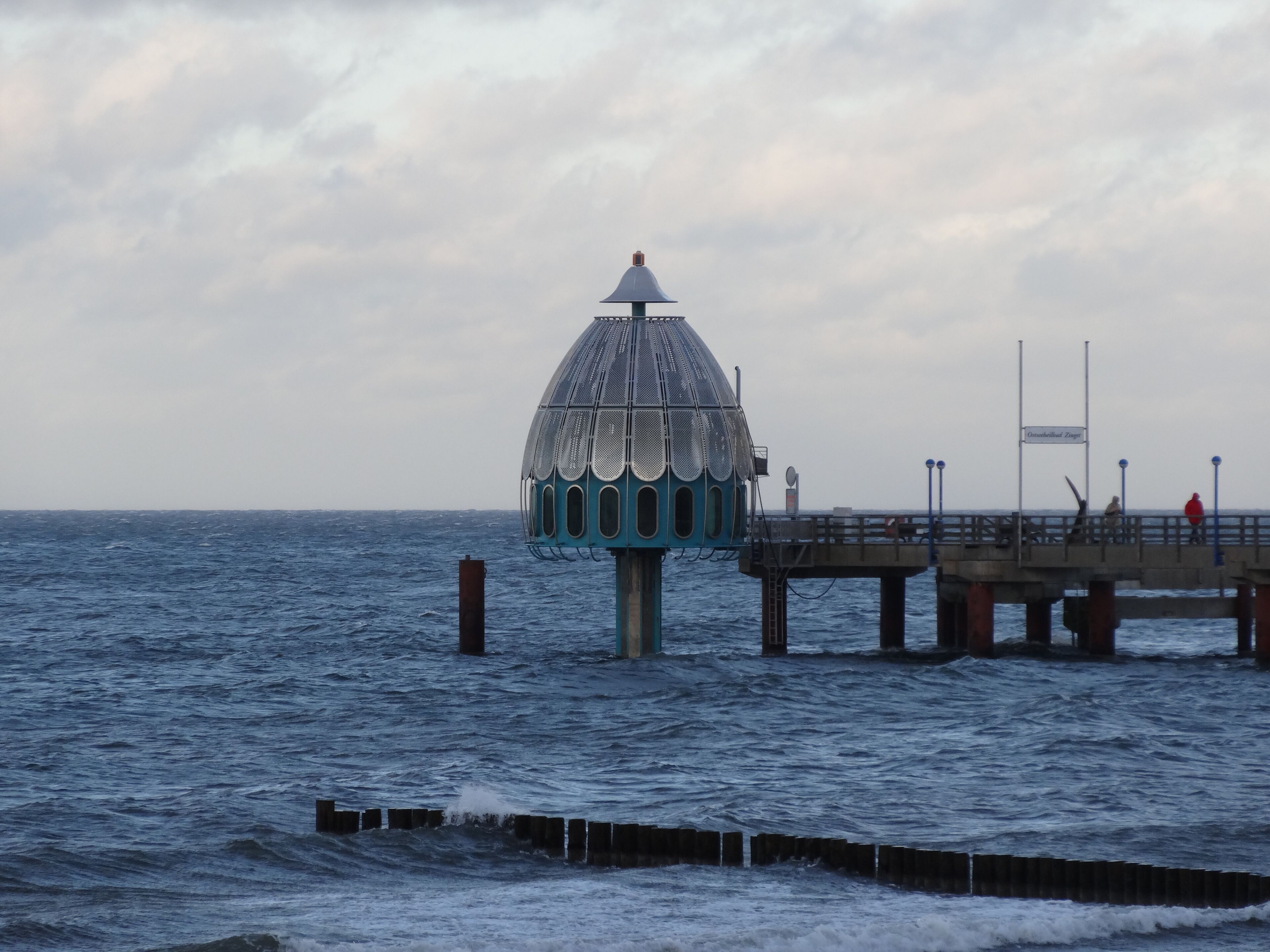 A pier extending into the sea with a gazebo-like structure at the end.