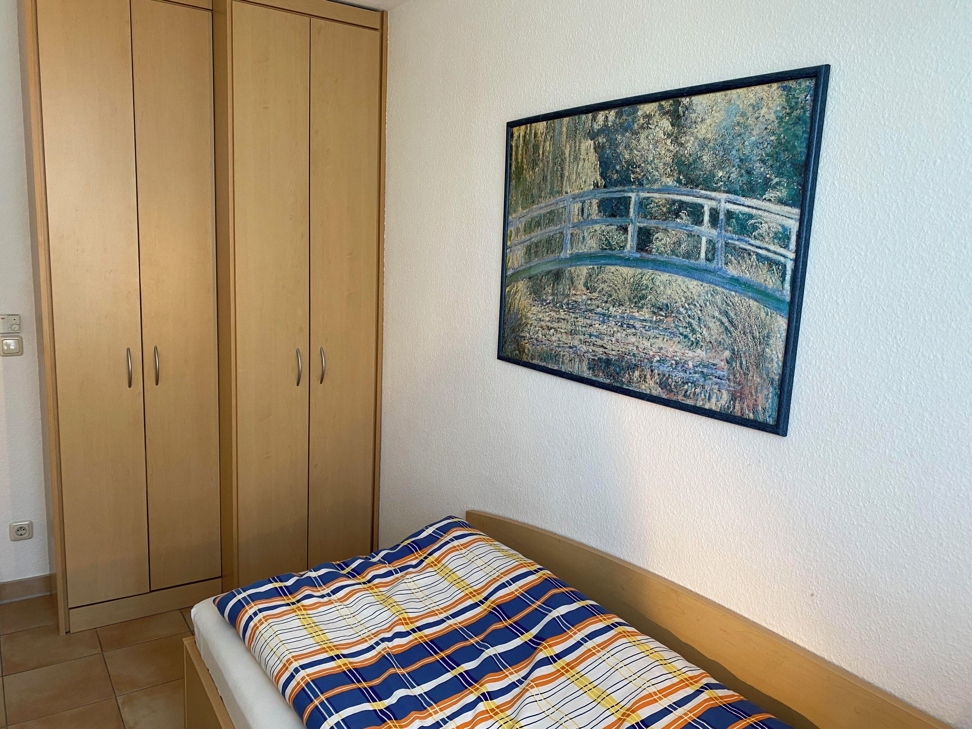 Ein Schlafzimmer mit einem Bett, einem Kleiderschrank und einem Bild von einer Brücke.