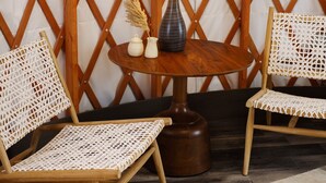 A room with a wooden lattice wall, two wicker chairs, a round wooden table with a lamp, and a patterned rug. - Frontier Drive Inn  (Center)