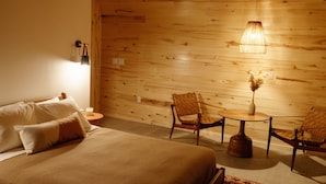 A room with a bed, two chairs, a small table, and a hanging light fixture. - Frontier Drive Inn  (Center)
