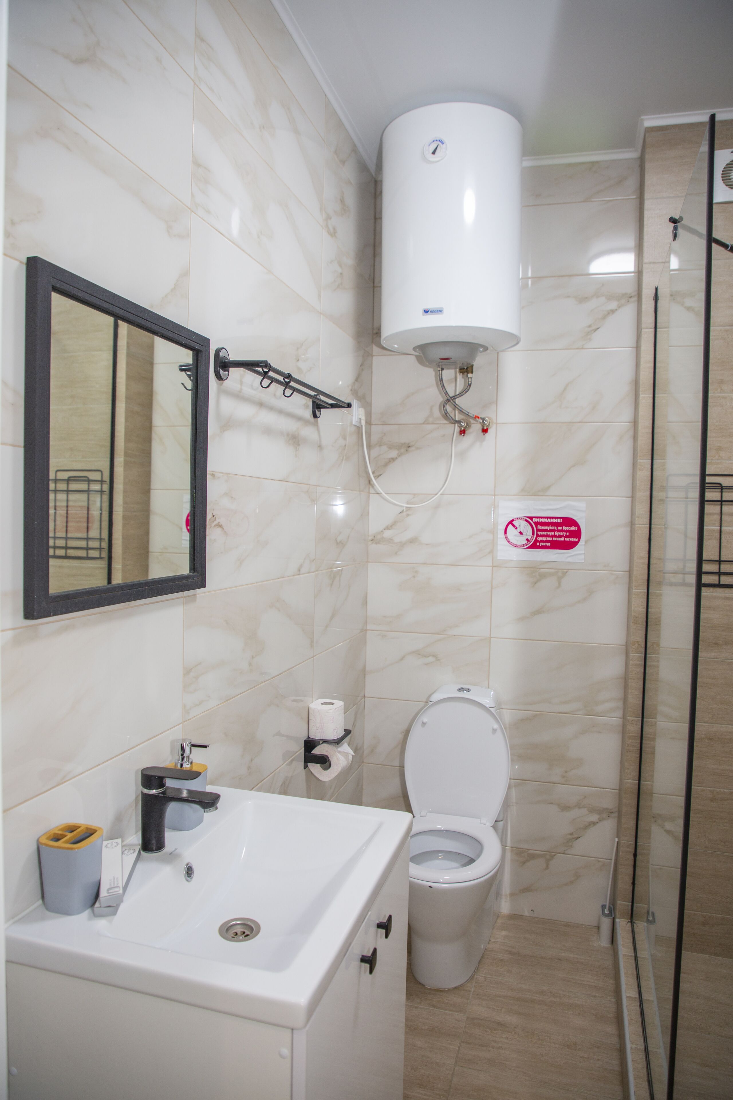 A bathroom with a white sink, mirror, toilet, and a shower area.
