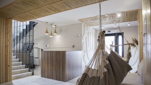 A spacious lobby with a hanging chair, a staircase, and a reception desk. - Silence hotel (Cholpon-Ata)