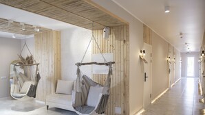 A modern hotel room with a wooden wall, a hanging chair, and a white sofa. - Silence hotel (Cholpon-Ata)
