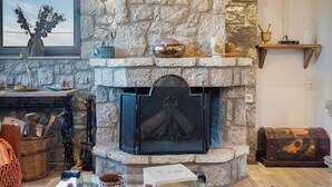 Una chimenea de piedra con un televisor encima, un estante de madera con adornos, y una mesa con teteras y tazas.